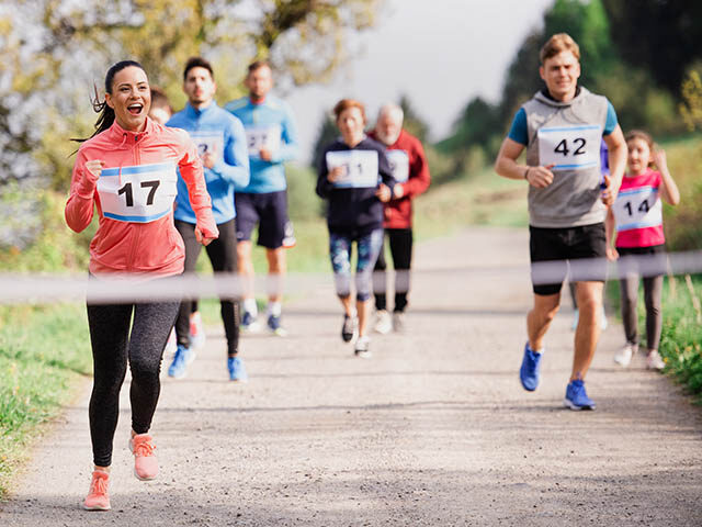 Large group of multi generation people running a race competition in nature.